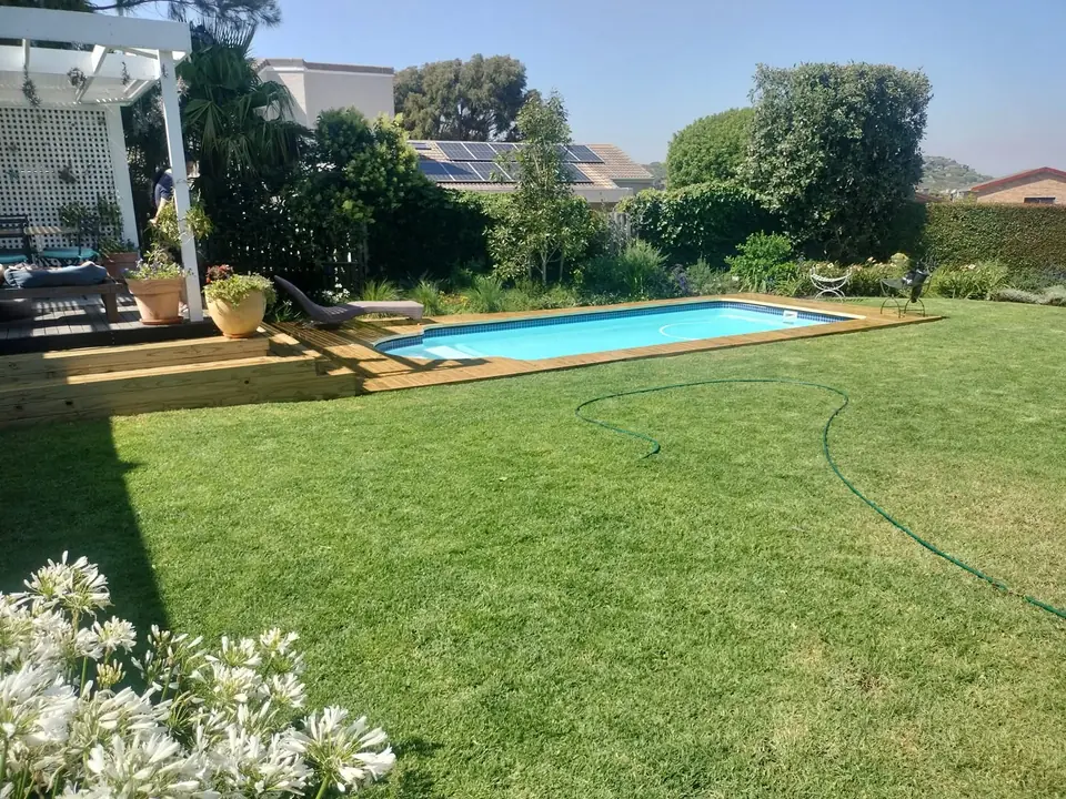 Lawn, swimming pool and timber deck in a landscaped garden